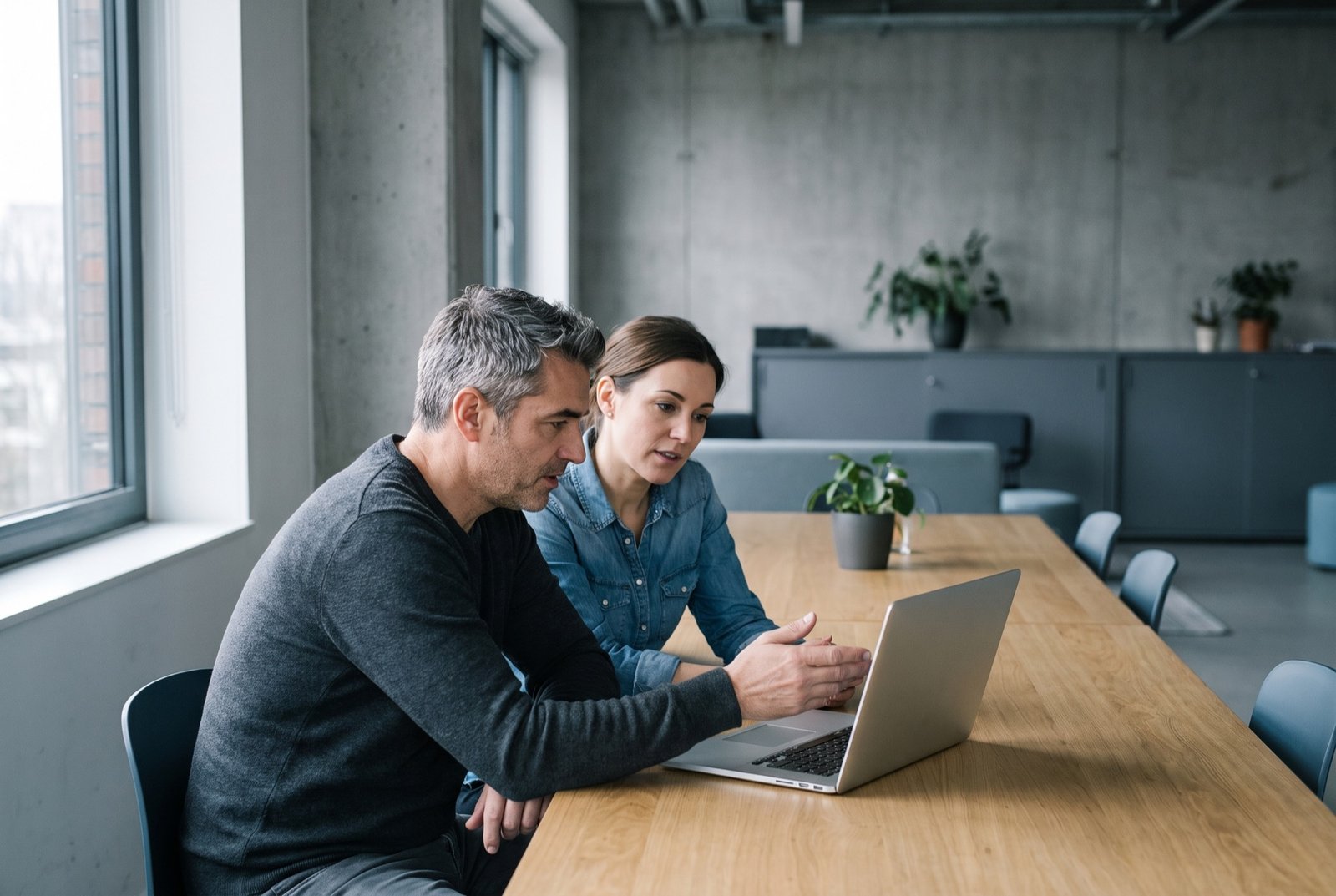 A mentor and a sales representative reviewing work together at one screen in a modern office.